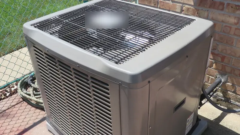 Outdoor central air conditioner condenser unit on a concrete pad next to a brick house